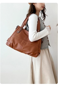 Dettaglio della borsa tote in pelle marrone vintage con cuciture a croce e trama martellata