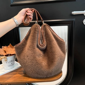 Brown leopard faux fur tote bag with leather handles shown in a lifestyle handheld view