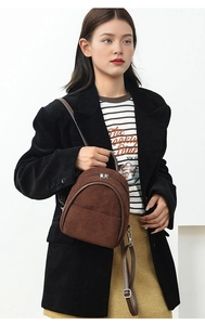 Detail of dark brown corduroy texture on a mini backpack with silver dual zippers