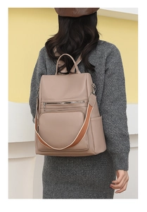 Detail of khaki PU leather backpack with lychee grain texture and woven shoulder strap