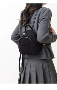 Detail of a black corduroy mini backpack with vertical texture and leather straps on a model