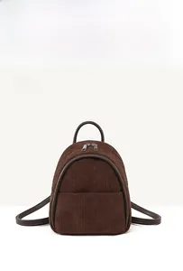 Detail of dark brown corduroy backpack showing ribbed texture and front zip pocket
