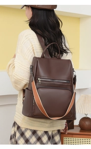 Deep brown pebble leather backpack with stylish orange woven strap shown on model back