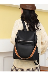 Close-up of black leather backpack with lychee texture and striped contrast strap detail