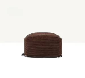 Detail view of corduroy backpack bottom with brown leather trim and metal hook