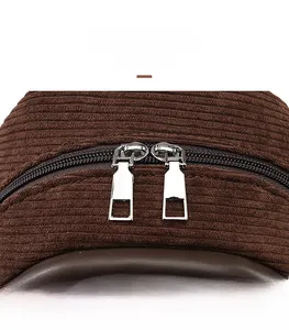 Detail of dual metal zippers and striped corduroy fabric texture on a brown backpack