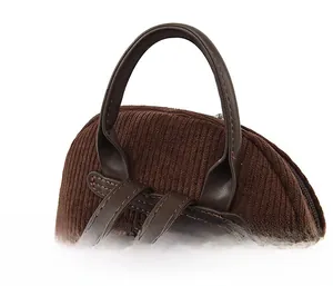 Detail of dark brown corduroy backpack showing the soft faux leather handle and texture