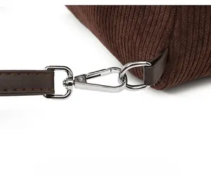 Detail of detachable shoulder strap with silver lobster clasp on brown corduroy bag
