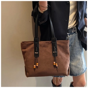Dettaglio borsa tote in pelle scamosciata marrone con perline di legno e manici neri