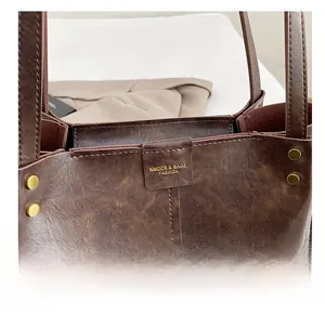 Close-up of vintage brown leather tote bag with rivets and brand leather tag