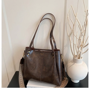 Detail of a large brown vintage tote bag featuring a textured finish and stylish wide strap