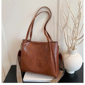 Close-up of brown tote bag with vintage texture and stylish ethnic woven shoulder strap