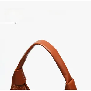 Dettaglio del manico della borsa tote in pelle intrecciata arancione e trama artigianale