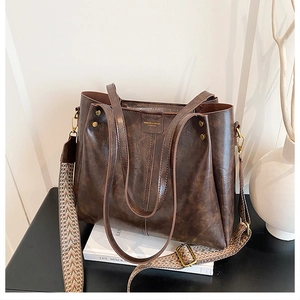 Detail of dark coffee tote bag with wide ethnic weave strap and gold hardware accents