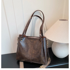 Close-up of dark brown tote bag with vintage texture and woven shoulder strap