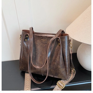 Detail of dark brown vintage faux leather handbag with colorful wide patterned strap