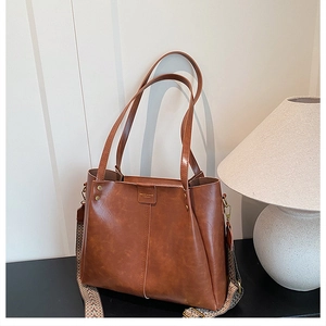 Detail of caramel leather tote with golden hardware and ethnic woven wide strap
