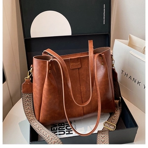 Macro detail of brown leather tote bag with stylish ethnic woven wide shoulder strap
