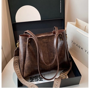 Detail of dark brown leather tote bag with ethnic patterned wide strap in a gift box