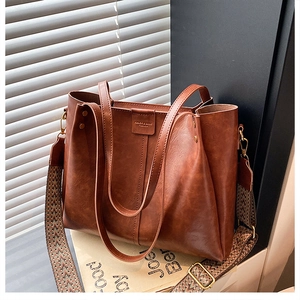 Close-up of brown PU leather tote bag with geometric jacquard wide strap and bronze hardware