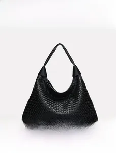 Dettaglio della trama in pelle intrecciata nera e del manico cilindrico della borsa tote