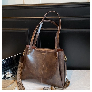 Detail of vintage oil-wax leather tote with wide geometric strap and golden hardware