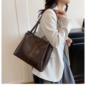 Detail of coffee brown leather tote bag with gold studs and vintage texture