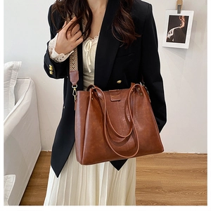 Brown leather tote with vintage texture and colorful woven shoulder strap details