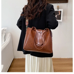 Close-up of brown faux leather tote with golden hardware and ethnic jacquard strap