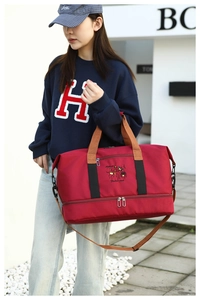 Detail view of large red travel bag with separate bottom shoe compartment and shoulder strap