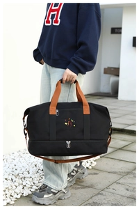 Detail of black travel bag with dry-wet separation pocket and brown woven straps