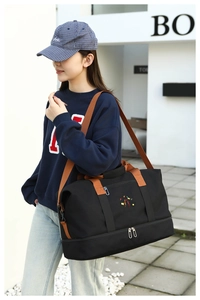 Detail view of black travel bag showing shoe compartment and durable shoulder strap