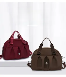 Detail of burgundy and dark brown nylon tote bags featuring stylish pleated front design
