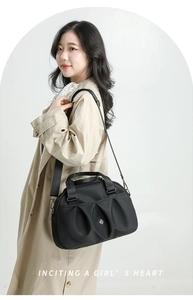 Detail of black pleated nylon tote bag with round logo and woven top handles on model