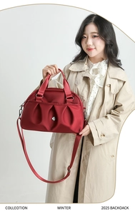 Close-up of deep red nylon tote bag with pleated front design and metal hexagon logo