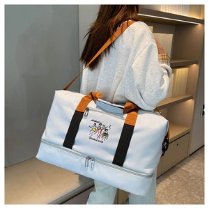 Detail of light blue travel bag featuring a bottom shoe compartment and cartoon embroidery