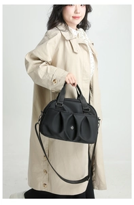 Detail of black pleated nylon handbag with dual handles and adjustable shoulder strap