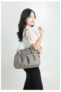 Detail of grey nylon handbag showing pleated texture, metal logo and adjustable strap