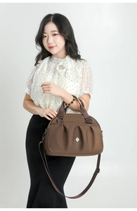 Asian model carrying a brown pleated nylon crossbody bag with silver logo detail