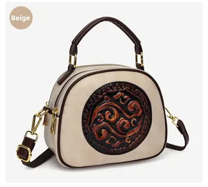 Detail of beige shell-shaped handbag featuring embossed floral emblem and leather texture
