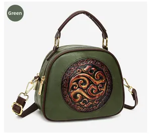 Detail of dark green embossed crossbody bag with traditional floral texture and brown trim