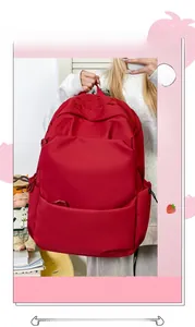 Detail of red nylon backpack showing gothic embroidery and spacious side pockets