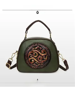 Detail of dark green retro handbag featuring embossed pattern and brown leather straps