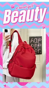 Close-up of a large capacity red nylon student backpack worn by a model in a trendy setting