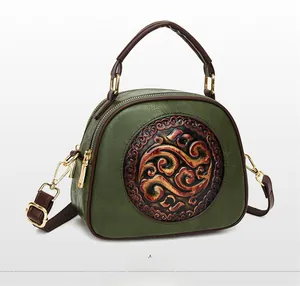 Detail view of dark green retro shoulder bag with embossed floral pattern and gold hardware