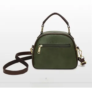 Detail of dark green shell bag with rear zipper pocket and brown leather handles