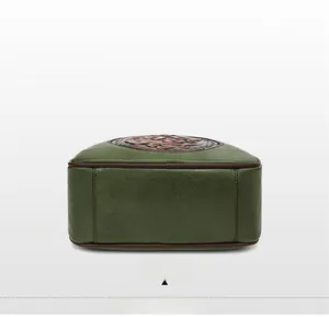 Detail view of the green leather handbag bottom with brown piping and neat stitching