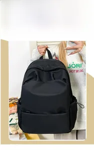 Detail of minimalist black backpack featuring functional drawstring side pockets and embossed text