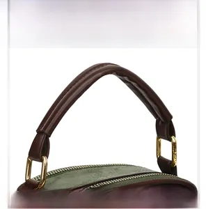 Close-up of green lychee leather texture and golden metal D-buckle detail on handbag