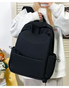 Detail of minimalist black large capacity backpack with side drawstring pockets and compartments